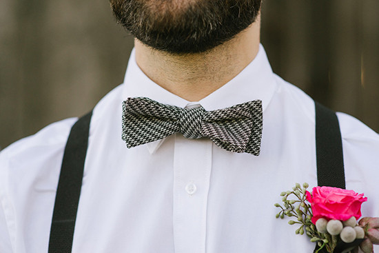 Groom with suspenders houndstooth bow tie and pink boutonniere