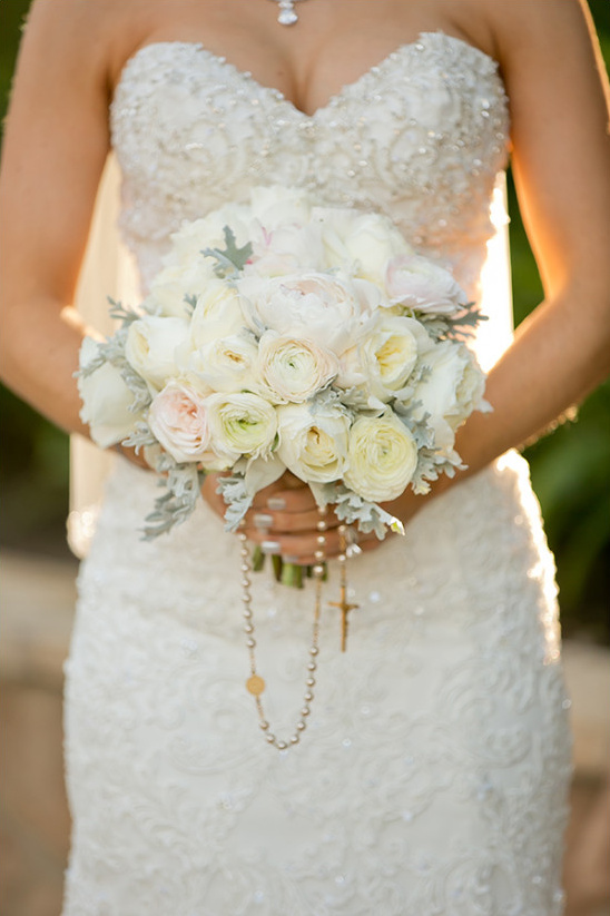 Bride in lace dress holding white ranunculus bouquet