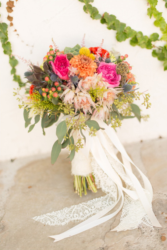 Vibrant wedding bouquet with roses and lace ribbon