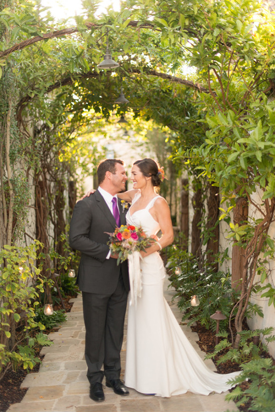 Bride and groom under garden archway on wedding day