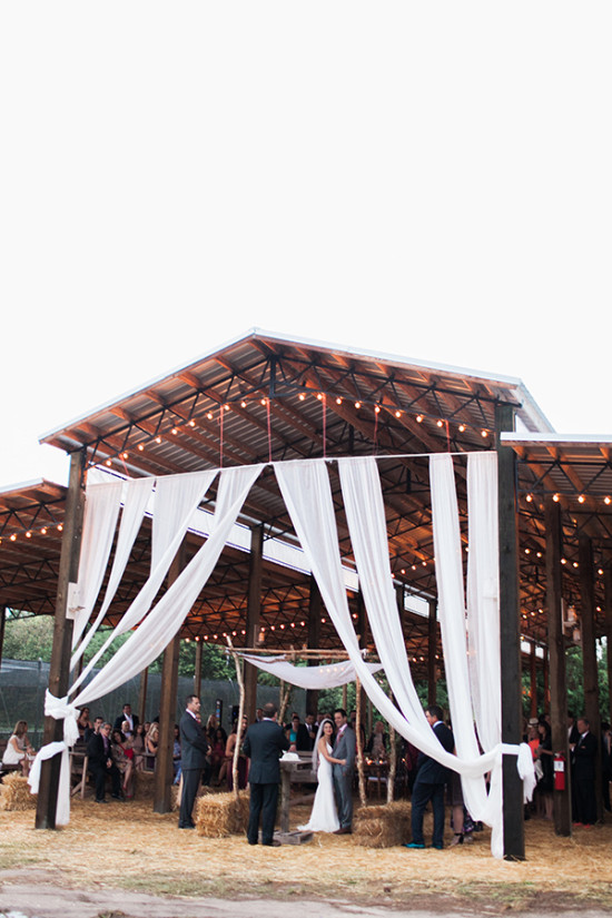 Barn wedding ceremony with white draping and string lights