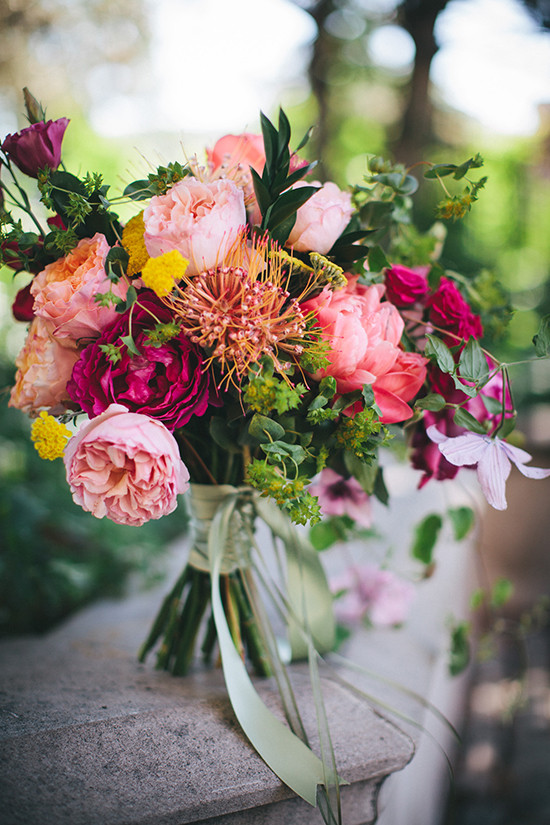 Vibrant bouquet of pink and red flowers tied with green ribbons
