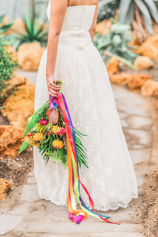 Bride holding a bouquet with colorful ribbons, a wedding dress