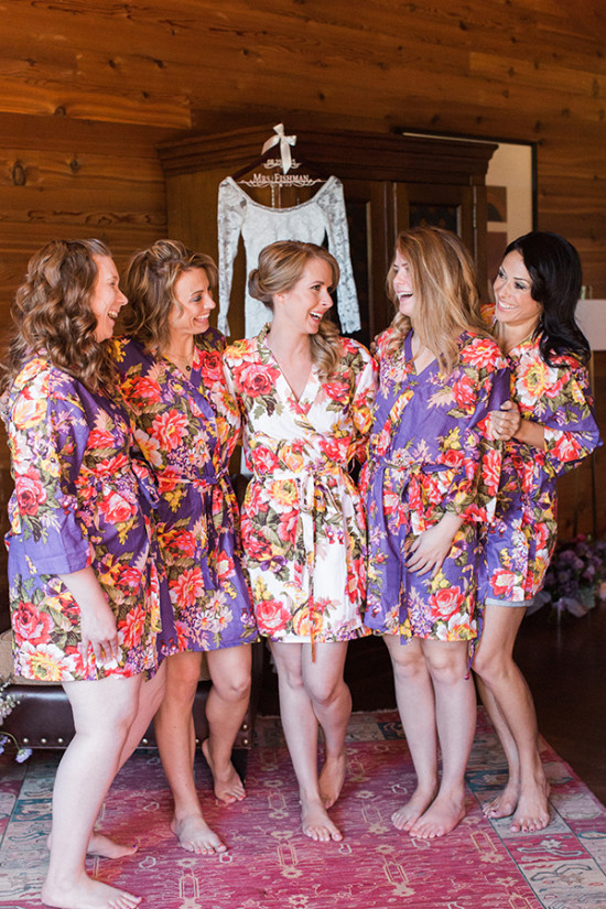 Bridesmaids laughing in floral robes, getting ready for the wedding