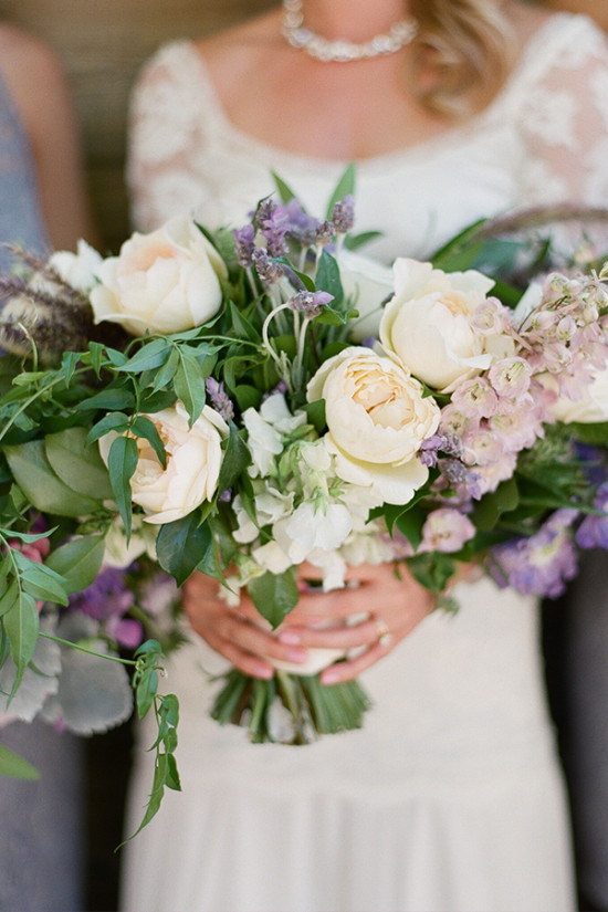 Bride holding a beautiful bouquet of cream and purple flowers