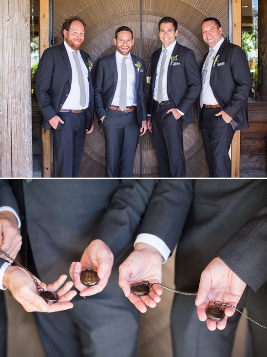 Groomsmen in suits smile and show pocket watches on a wedding day