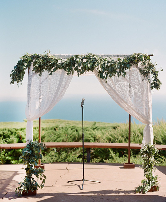 Wedding arch decorated with leaves and sheer white fabric