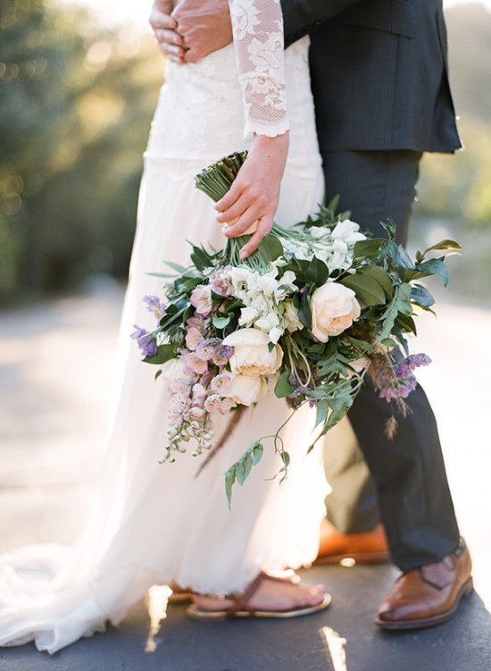 Bride and groom embracing, holding a floral bouquet at a wedding