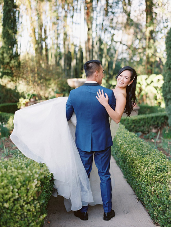 Groom carries smiling bride in garden wedding photo