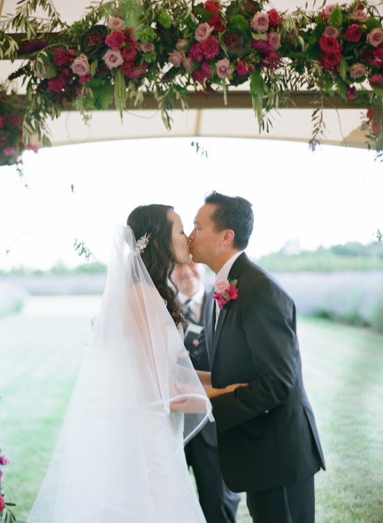 kissing under a purple rose wedding arch