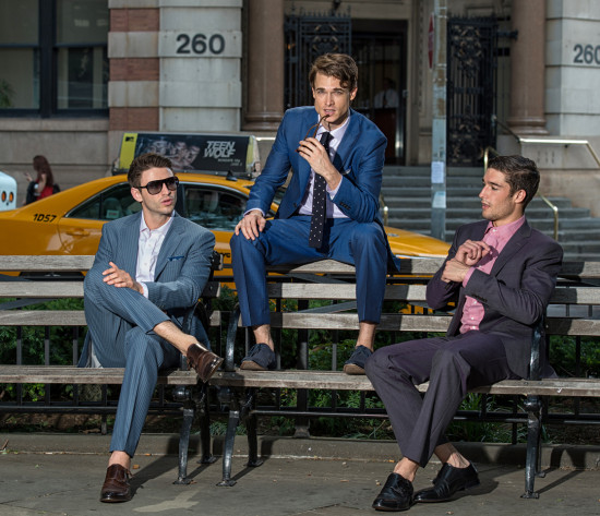 Three stylish men in suits sitting on a bench in New York City