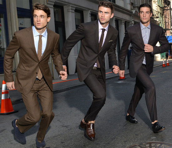 Three men in stylish suits run through a city street together
