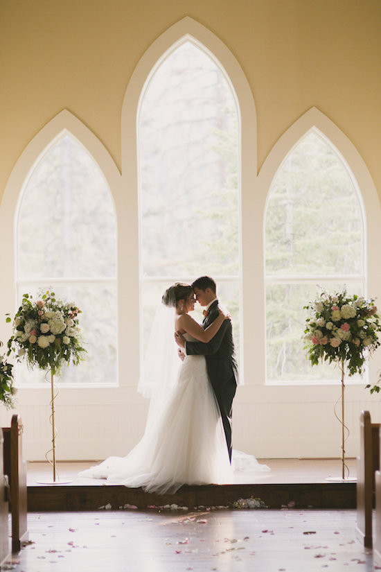 Newlyweds embrace in a light-filled church during their wedding ceremony