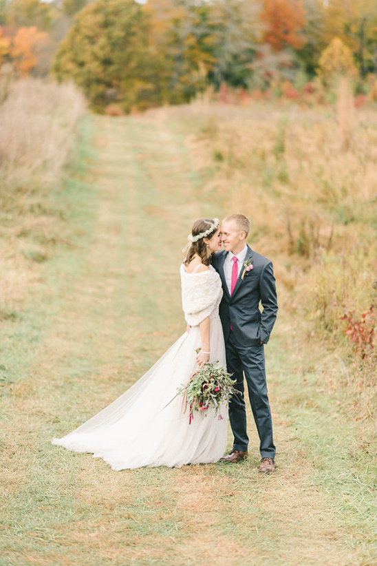 Wedding couple embracing in a field of golden grass and autumn trees