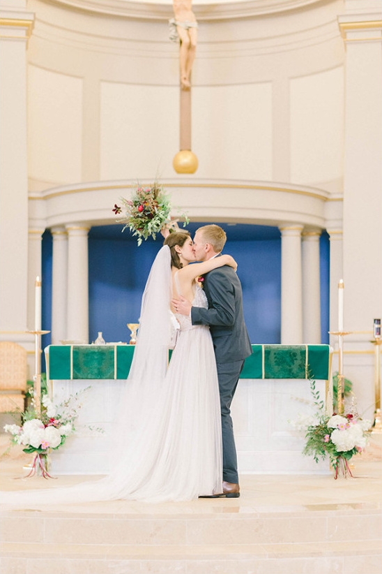 Newlyweds share a kiss at the alter of their wedding ceremony