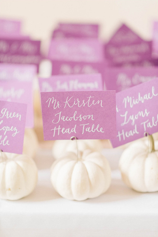 Wedding place cards with names on pink paper over white pumpkins