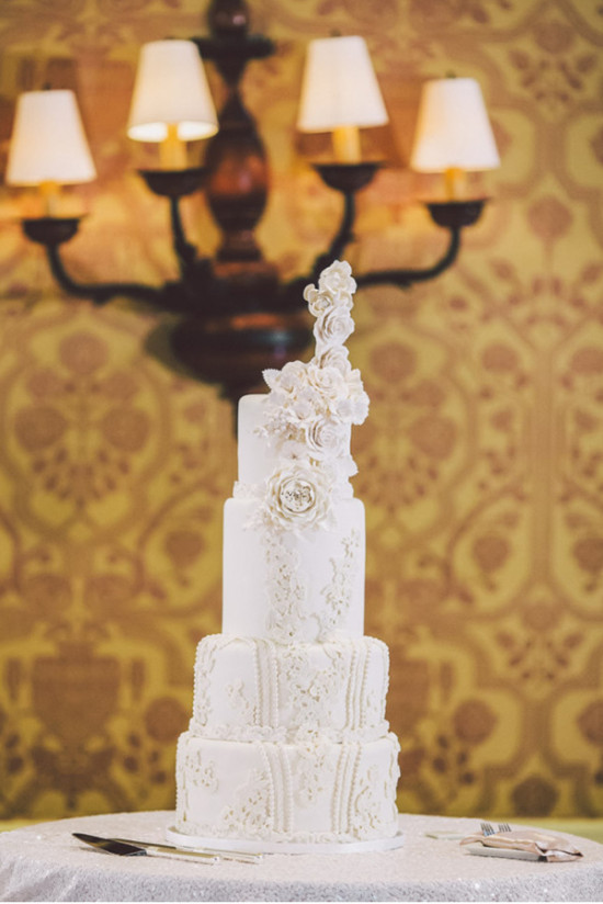 Elegant white wedding cake with floral details in a decorated hall