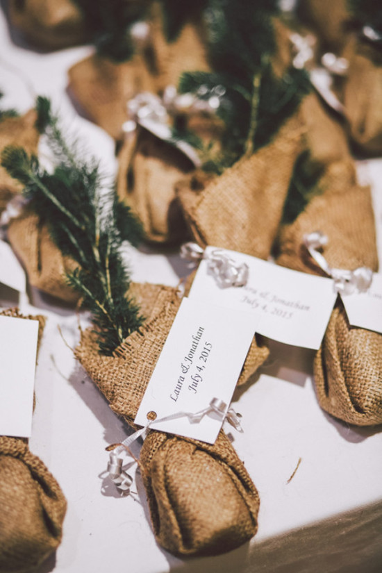 Wedding favors in burlap bags with greenery and name tags