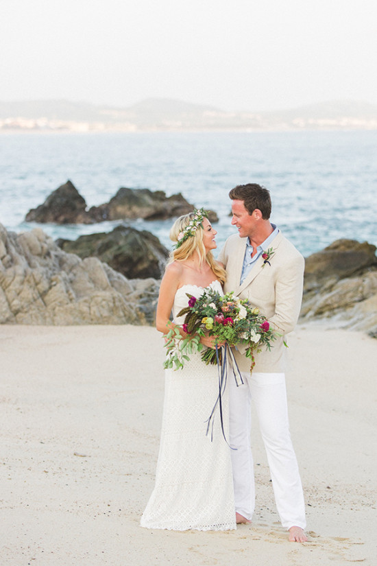 Beach wedding couple smiling at each other with ocean background