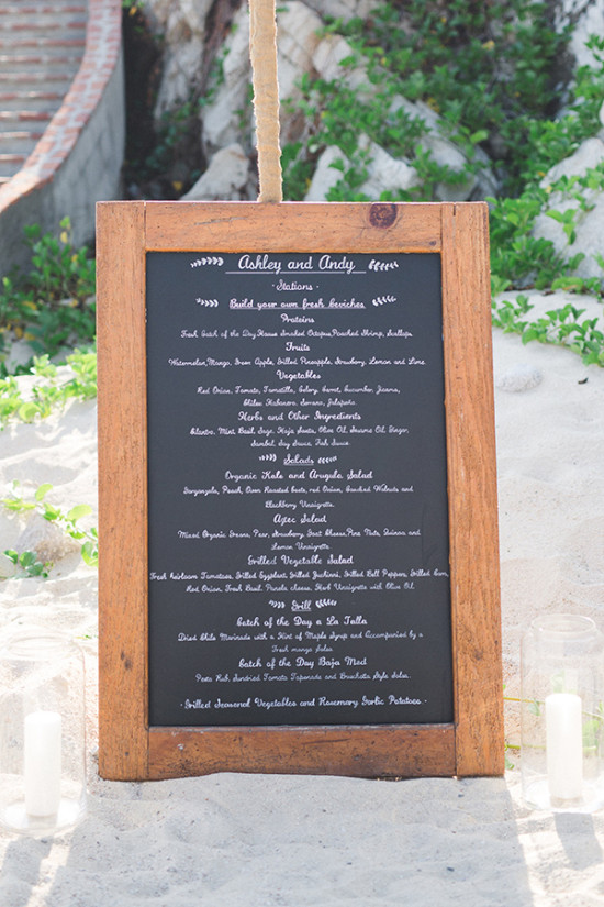 Wooden framed wedding menu sign on the sand with meal options