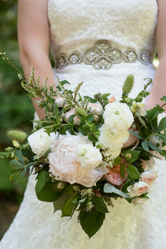 Bride holding elegant bridal bouquet with lace dress detail