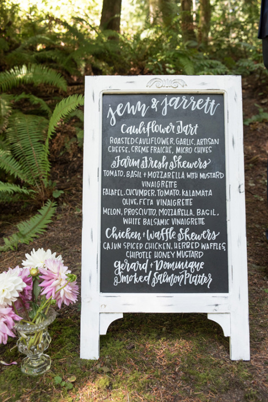 Wedding menu sign with handwritten food options in a forest setting