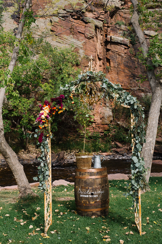 Wedding arch decorated with flowers and barrel, outdoor ceremony setup
