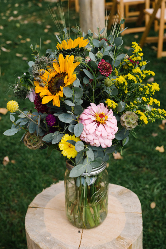 A vibrant bouquet of sunflowers and colorful flowers in a mason jar