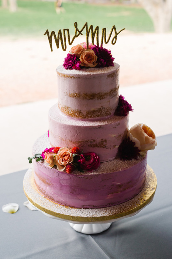 Three-tiered wedding cake decorated with flowers and mr and mrs topper