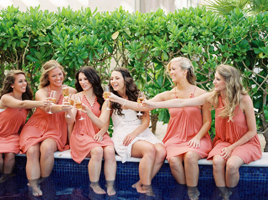 Bridesmaids celebrating with champagne by the pool, a wedding toast