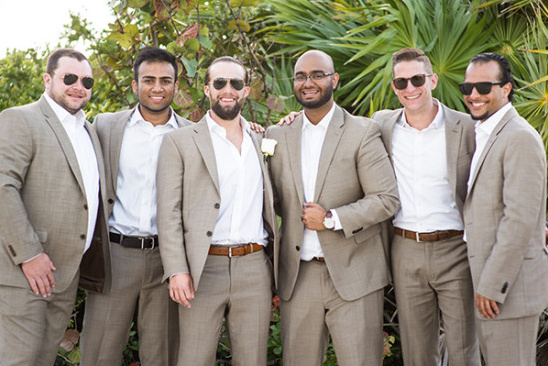 Group of groomsmen smiling in matching suits and sunglasses