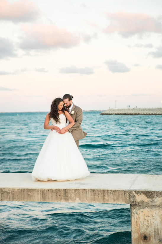 Couple embracing on a pier by the ocean on their wedding day