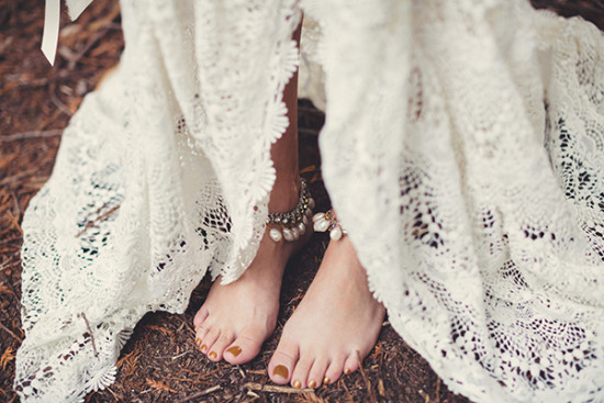 Bride's feet in lace dress with anklets standing on the ground
