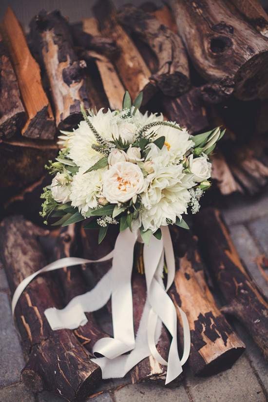 Elegant white bridal bouquet with flowing ribbons on wood