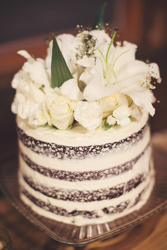 Delicious naked cake decorated with white flowers and greenery