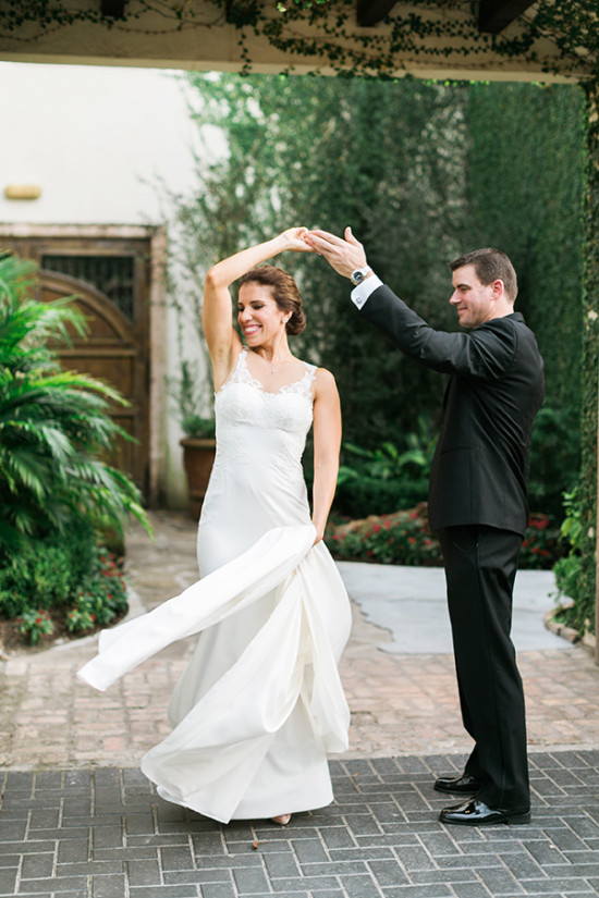 A happy couple dances at their wedding, surrounded by greenery
