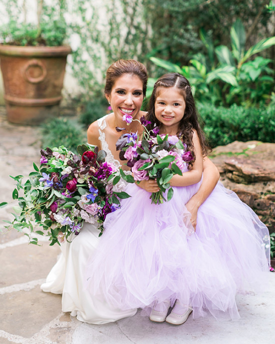 Bride and flower girl smiling with bouquets in a garden setting
