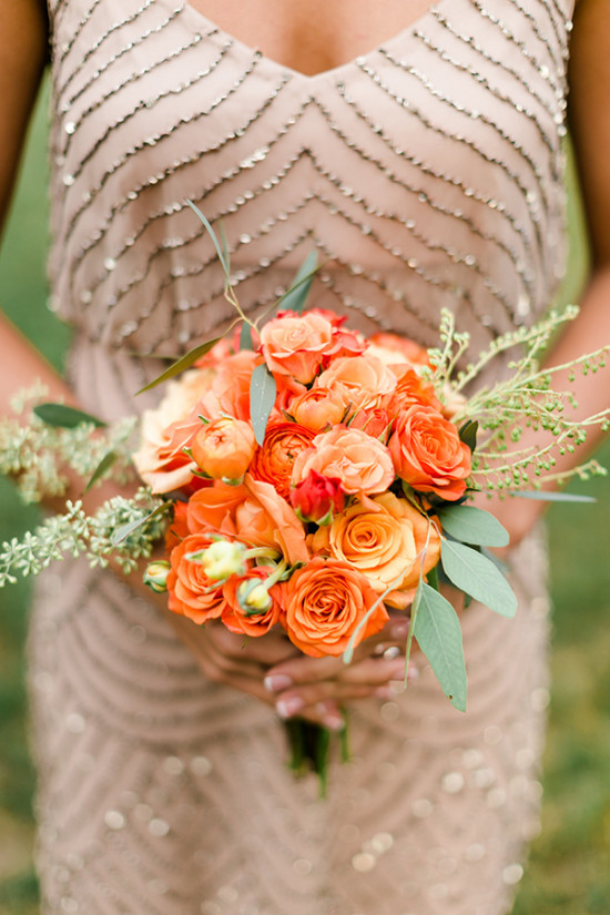 Woman holding a vibrant orange rose bouquet and wearing a dress
