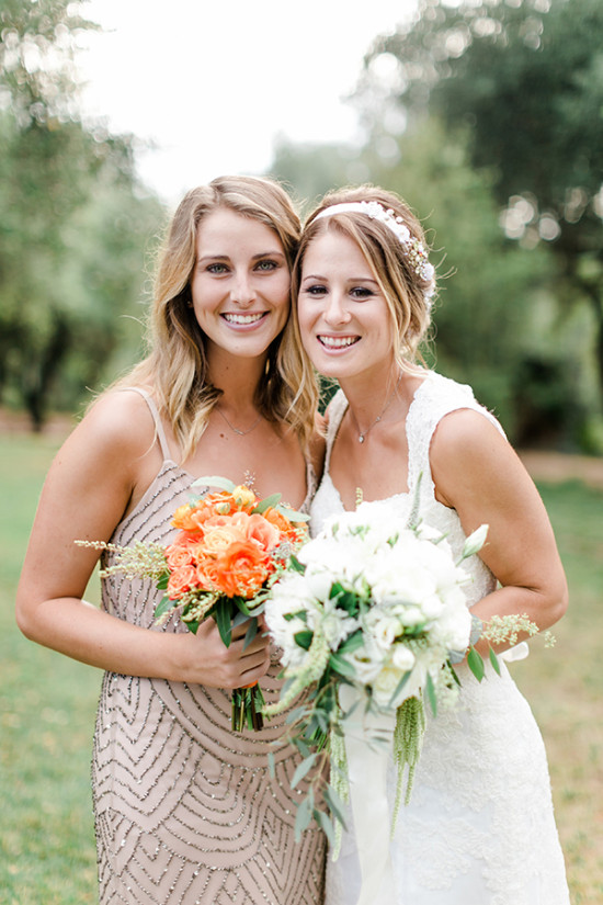 Two smiling women with bouquets at a wedding celebration