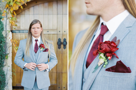 Groom with long hair in a light grey suit with a maroon boutonniere