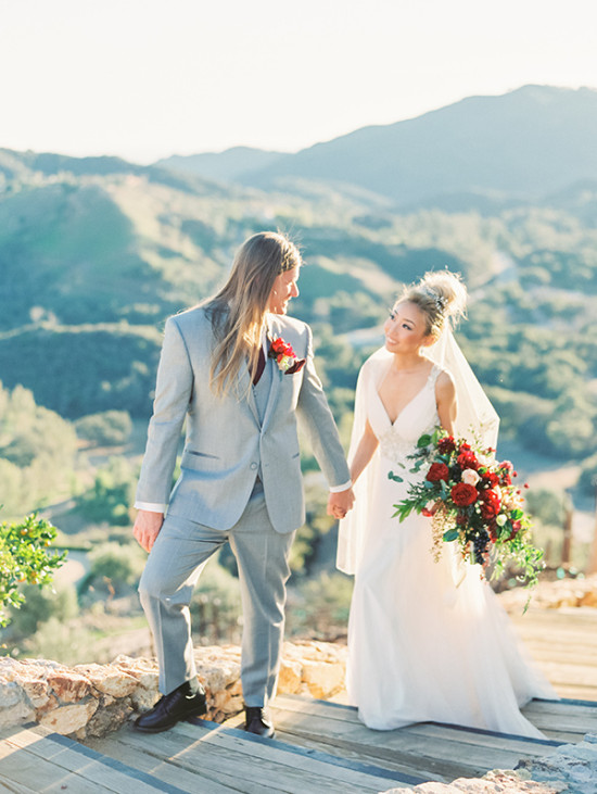 A just-married couple holding hands against a scenic mountain backdrop