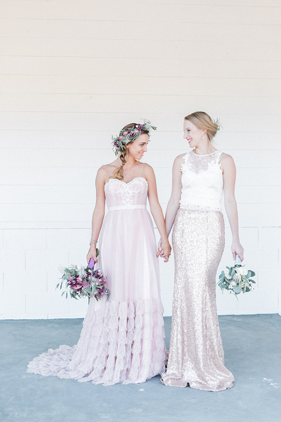 Two brides holding hands in wedding gowns