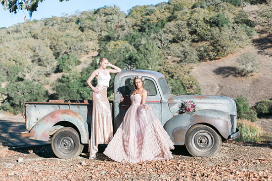 Two models pose by a vintage truck in elegant dresses