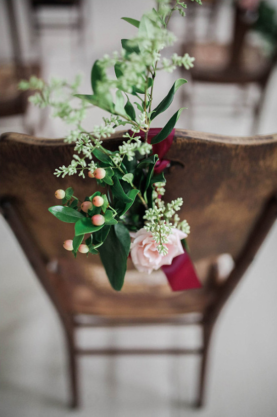 Floral arrangement on wooden chair back wedding decor