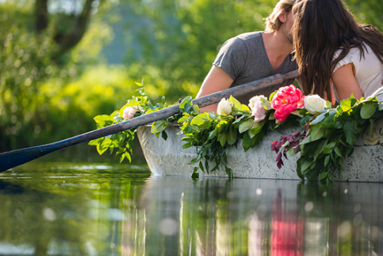 Romantic couple kissing in flower boat on calm lake