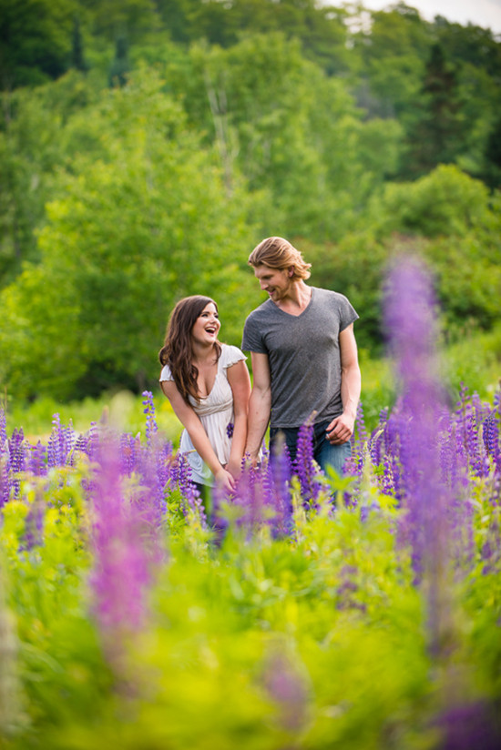 Smiling couple in love walks through purple lupine field