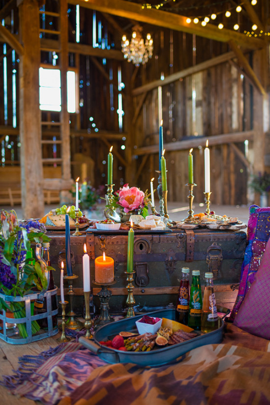 Bohemian picnic setup in barn with candles and food