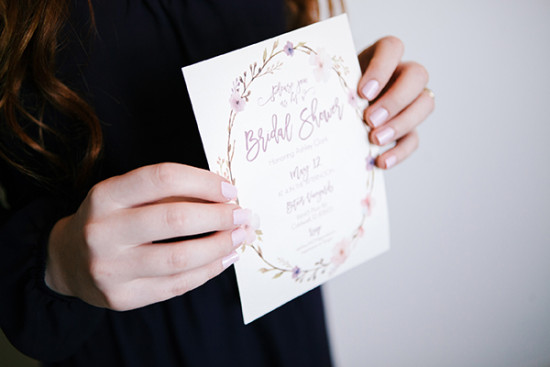 Floral bridal shower invitation held in soft focus hands