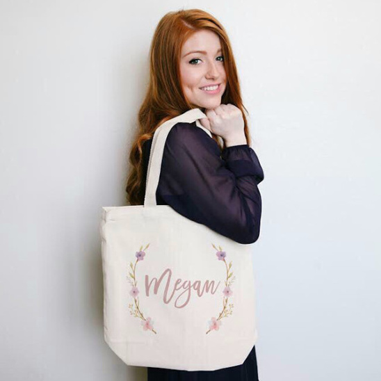 Smiling redhead woman holds Megan personalized floral tote bag