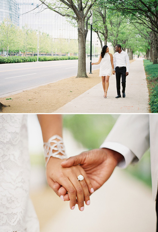 Engaged couple holds hands walking on a sidewalk near city